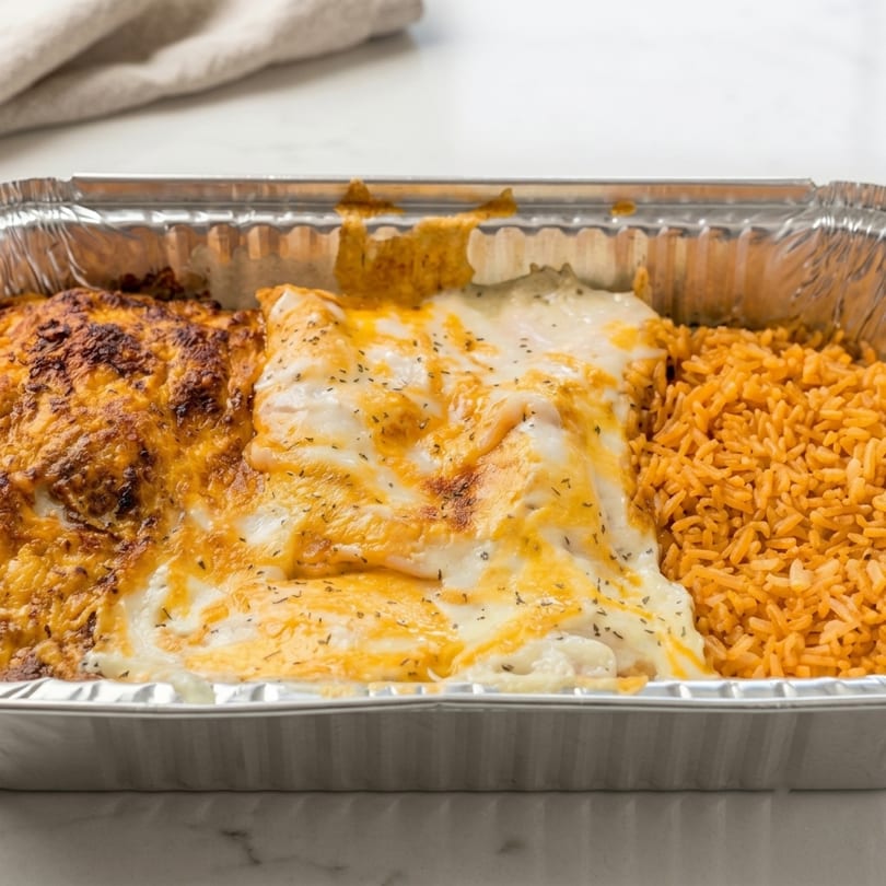 Cheesy enchiladas with red rice in a foil takeout container.